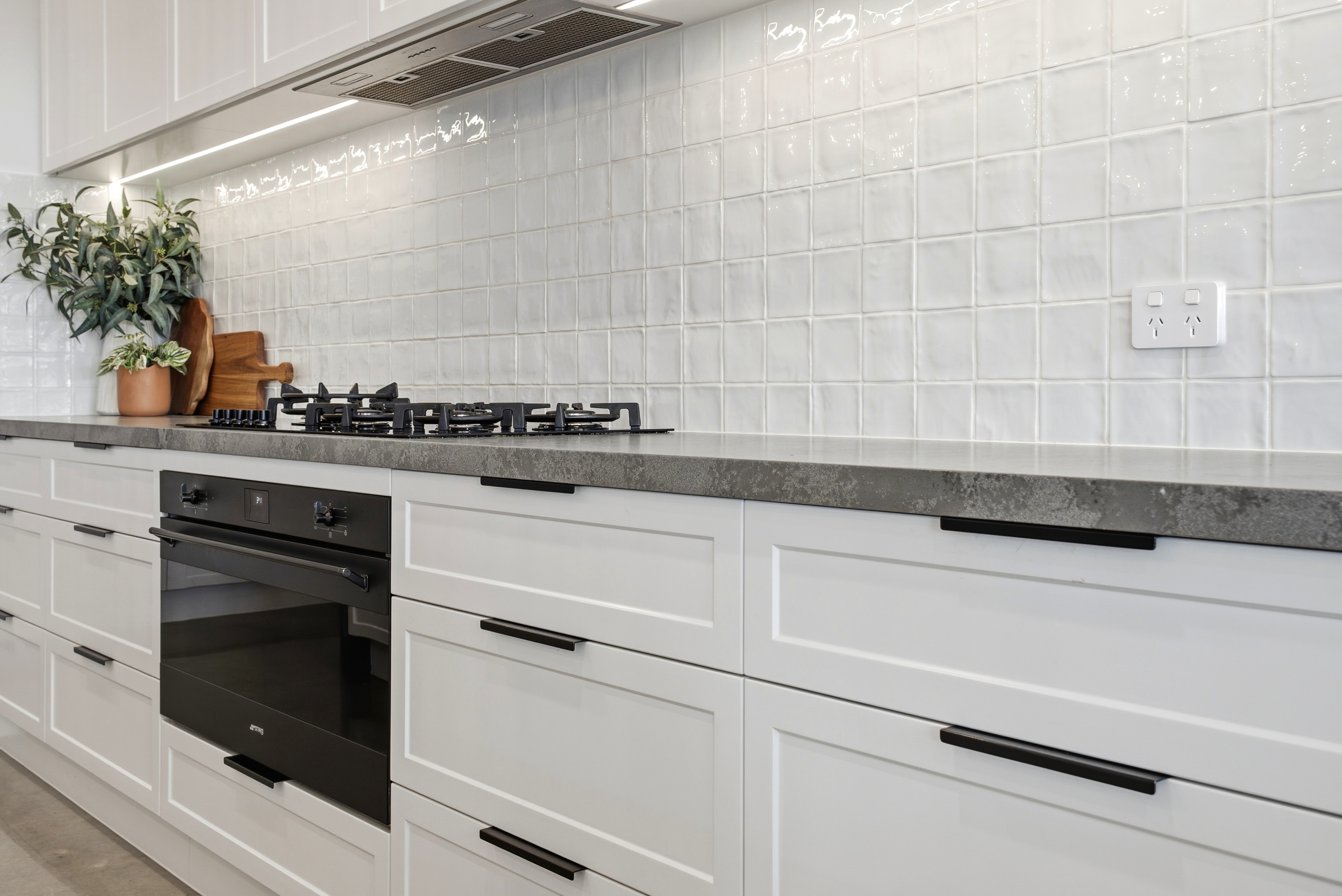 Stone benchtop, gas cooktop and handmade-look splashback tiles