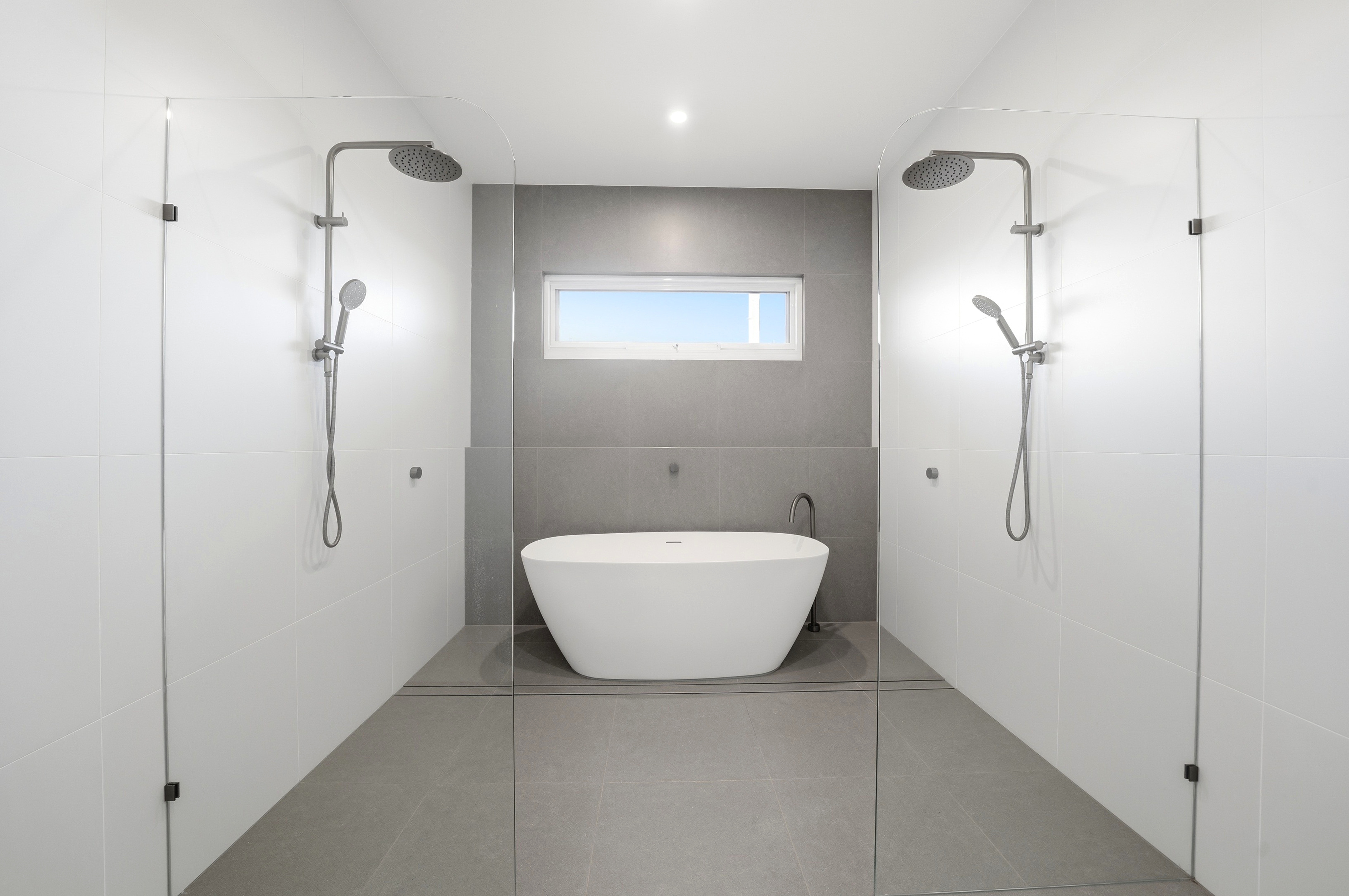 Freestanding bath framed by his-and-hers showers