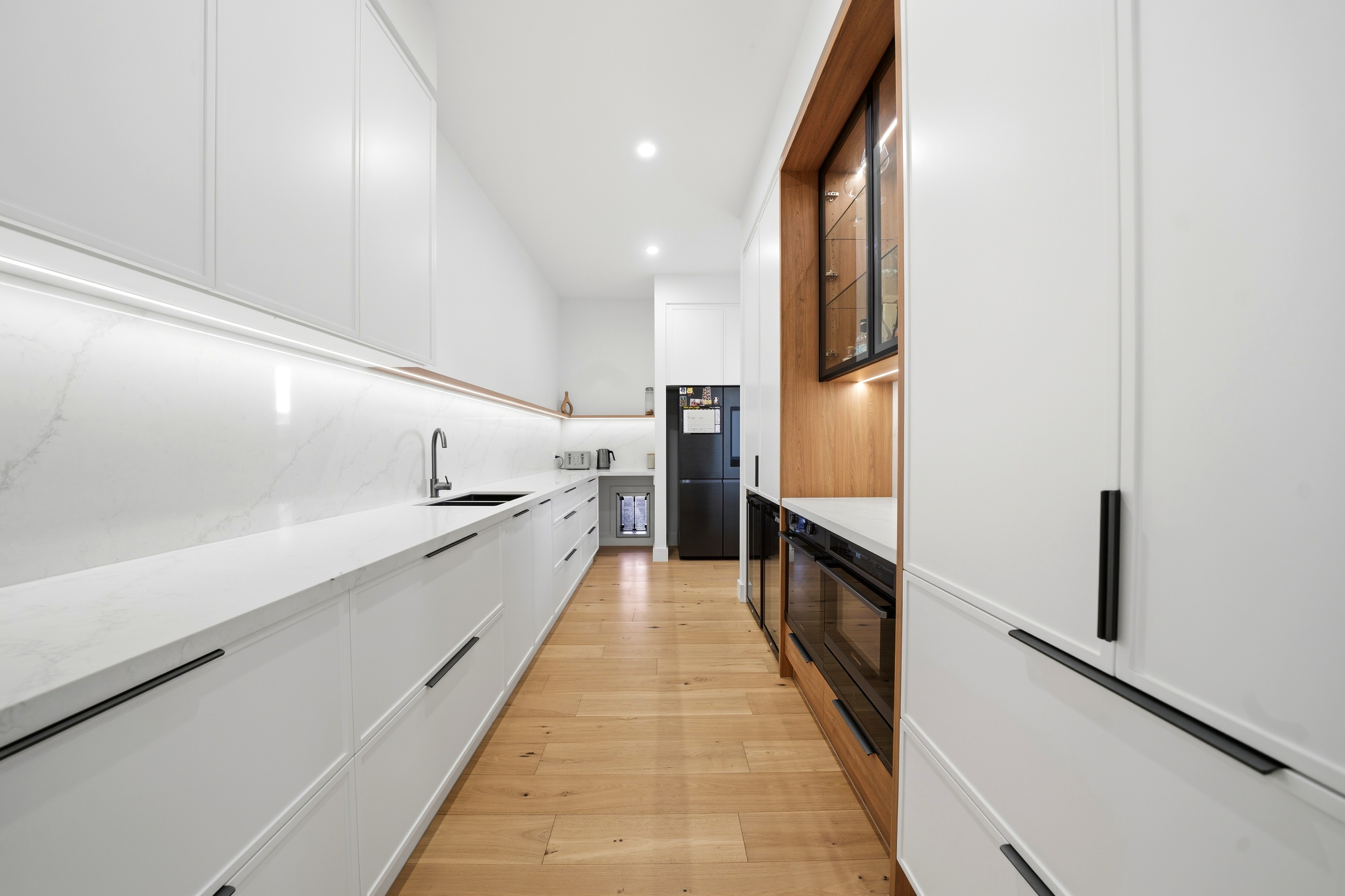 Butler's pantry with stone benchtops and integrated appliances